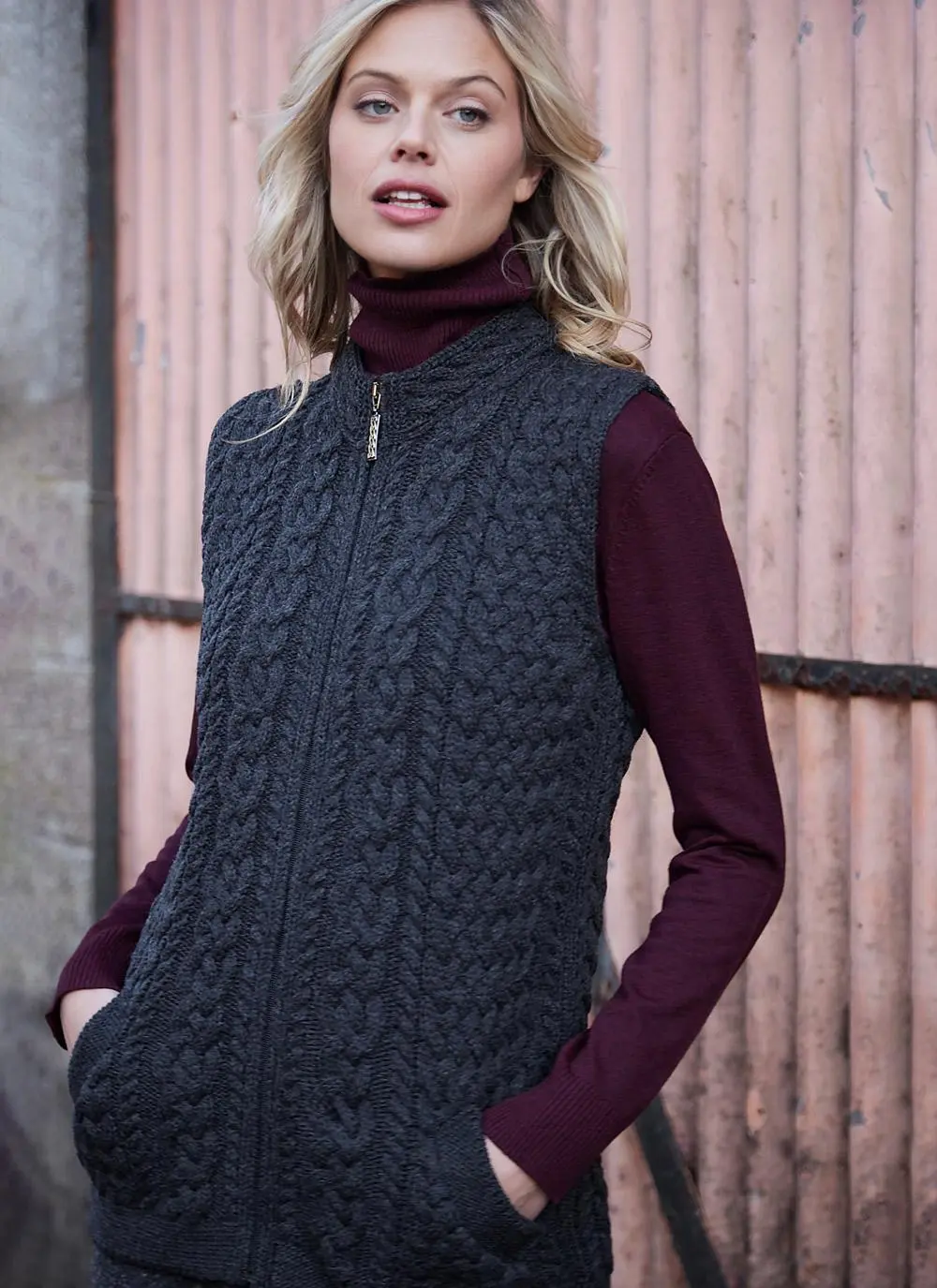 Women standing in front of pink door wearing charcoal aran gilet