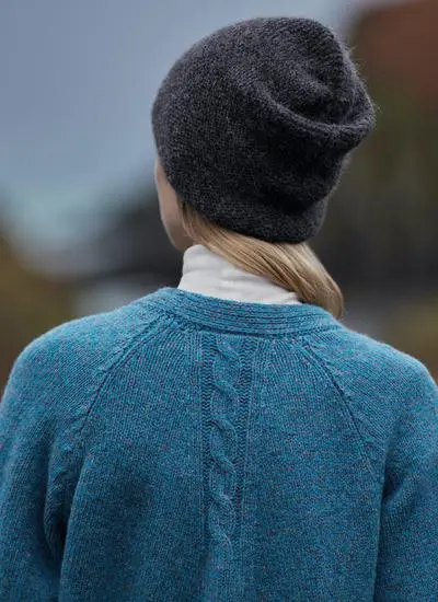close up back shot of woman woman wearing a blue cardigan and a grey beanie