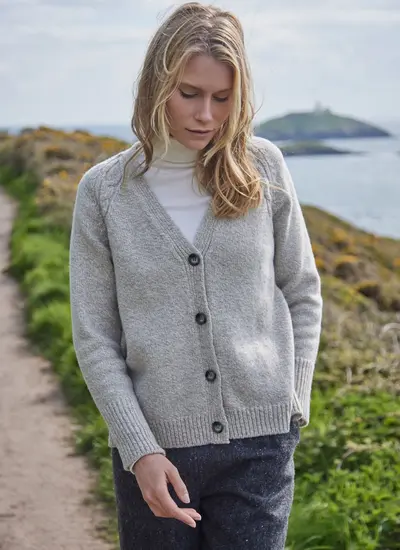 Grey colored knit cardigan, ribbed cuffs and hem, with model on a cliff walk