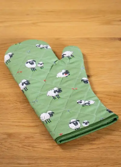 green gauntlet with sheep motif on tabletop