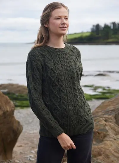 woman standing in stony beach wearing army green aran sweater