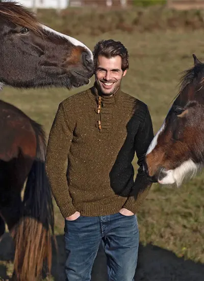 Man wearing olive Fisherman sweater with two horses