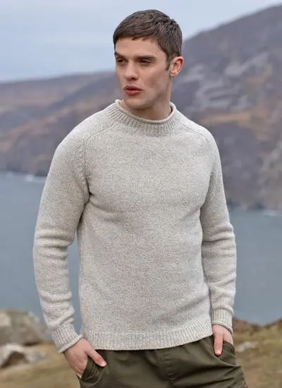 man wearing cream knit sweater with Irish landscape in background