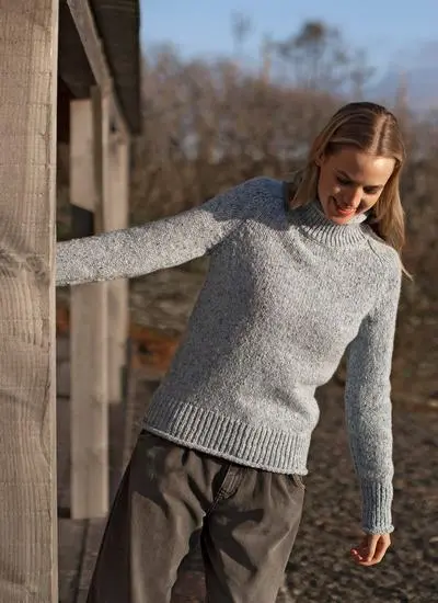 blonde woman wearing blue sweater swinging from stable