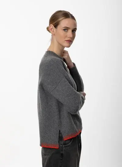 studio shot of woman standing grey sweater with arms folded