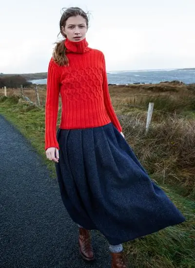 woman walking down rural pathway in ireland wearing a bright red polo neck sweater and long skirt