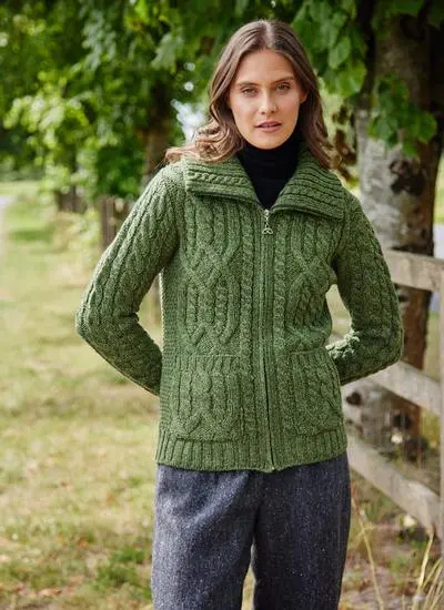 brown haired woman standing in park wearing a green zip up aran cardigan with black top underneath