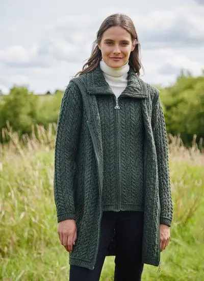 smiling brunette woman standing in field wearing open army green long cardigan