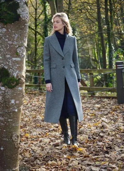 Blonde woman in woodland area wearing longline blue herringbone tweed coat