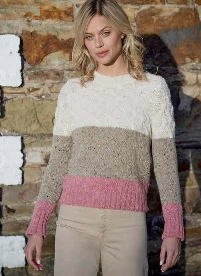 Woman wearing a tri-colored cable sweater- colors white, beige and pink